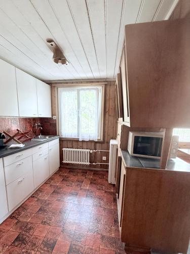 a kitchen with white cabinets and a tile floor at Hotel Guidon Apartments in Bivio