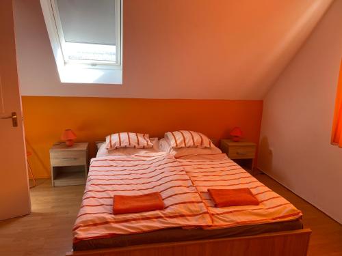 a bedroom with a bed with orange walls and a window at Panni Vendégház in Egerszalók