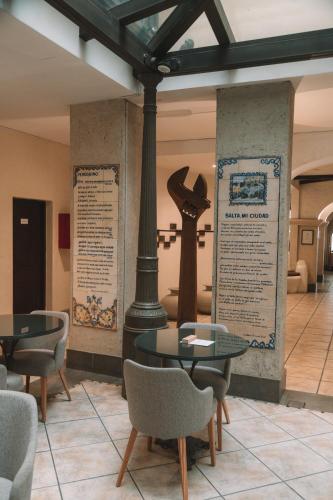 a room with two tables and chairs and a cross at Hotel Almería in Salta