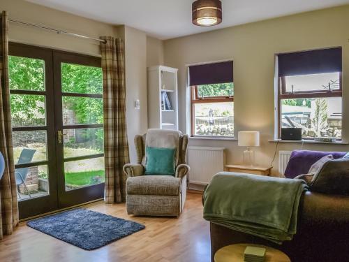 a living room with a couch and chairs and windows at Lime Tree Cottage in Drumpark
