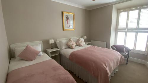 a bedroom with two beds with pink and white sheets at Harbour House B&B in Courtown