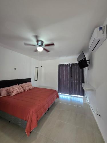 a bedroom with a red bed and a ceiling fan at Casa Moderna en Fraccionamiento in Caucel