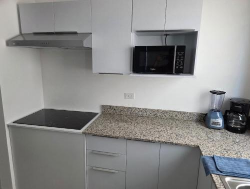 a kitchen with white cabinets and a black microwave at Casa Moderna en Fraccionamiento in Caucel