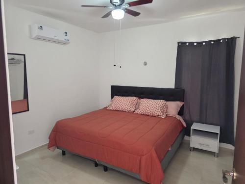 a bedroom with a red bed with a ceiling fan at Casa Moderna en Fraccionamiento in Caucel