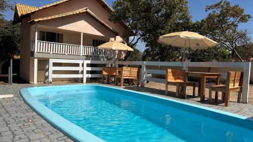 a pool in front of a house with a table and umbrella at Pousada Cipó in Serra do Cipo