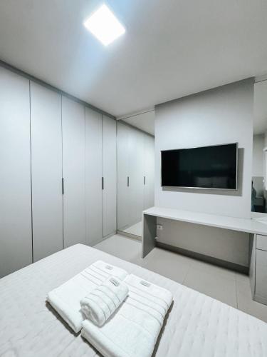 a white room with a bed and a flat screen tv at APTO 100% Climatizado - Experiência Premium - Único na Cidade - Garagem Privativa p/ carros ñ atende caminhonetes. in Três Lagoas