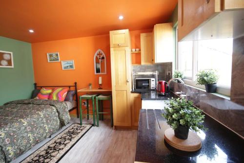 a bedroom with orange walls and a bed and a kitchen at Georgias Gate Studio Cottage - Sleeps 4 & Pets Ok in Errill