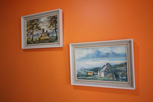 two framed paintings hanging on an orange wall at Georgias Gate Studio Cottage - Sleeps 4 & Pets Ok in Errill