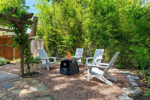 Tres sillas y una mesa y una fogata en un patio. en Peach Haus - Hot Tub & Fire Pit, en Fredericksburg