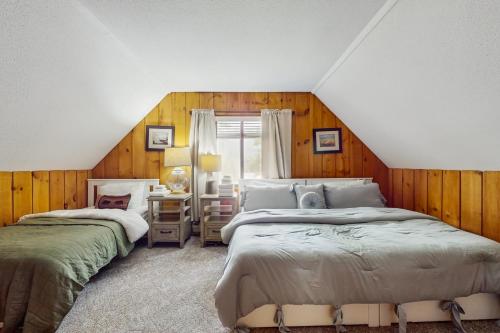 two beds in a room with wooden walls at Ski Haus Retreat in West Dover