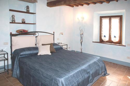 a bedroom with a bed with a blue blanket at La terrazza di Susanna in Peccioli