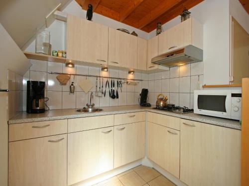 a kitchen with white cabinets and a microwave at Holiday Home in Nunspeet near Forest in Nunspeet