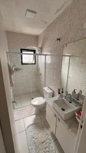 a white bathroom with a toilet and a sink at Casa aconchegante in Maresias