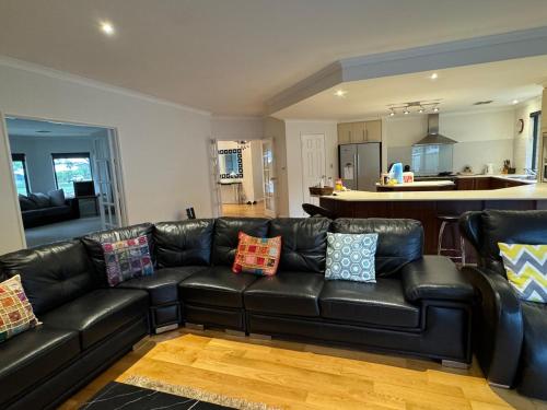 a living room with a black leather couch with pillows at Coastal Retreat - Secret Harbour in Secret Harbour
