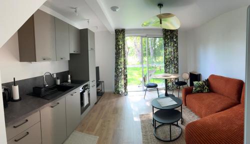 a kitchen and living room with a couch and a table at House in a residence with swimming pool near Le Touquet Paris Plage in Saint-Josse