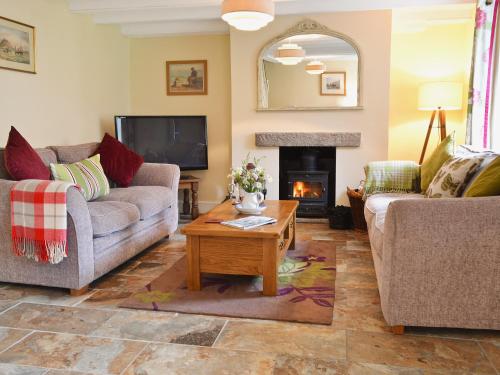 a living room with two couches and a fireplace at Sunloch Cottage in St Just