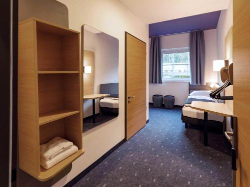 a hotel room with a mirror and a bedroom at B&B HOTEL Klagenfurt-City in Klagenfurt