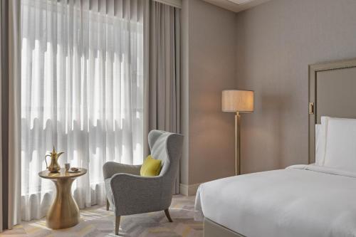 a bedroom with a bed and a chair and a window at Jumeirah Jabal Omar Makkah in Makkah