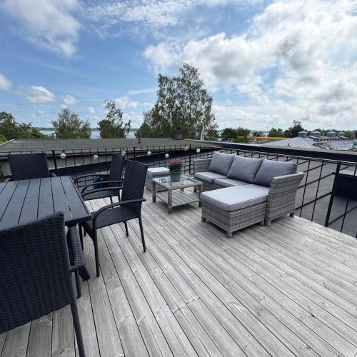 a deck with a couch and chairs and a table at Strandis in Mariehamn