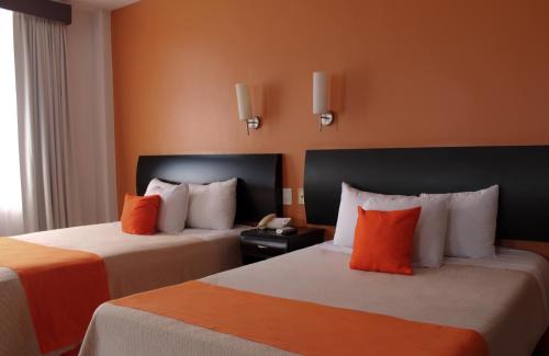 a hotel room with two beds with orange walls at Hotel Baez Paraiso in Paraíso