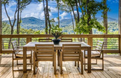 a wooden table with chairs and a potted plant on a deck at Mountain Majesty - Views Style & Relaxation in Morganton