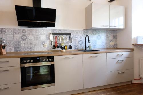 a kitchen with white cabinets and a stove top oven at Ferienwohnung Fränkischer Hof in Kail