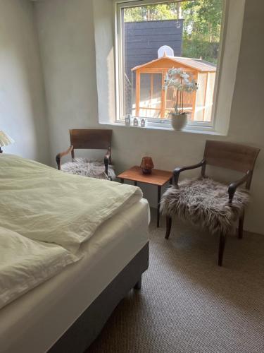 a bedroom with a bed and two chairs and a window at Winding B&B Silkeborg in Silkeborg