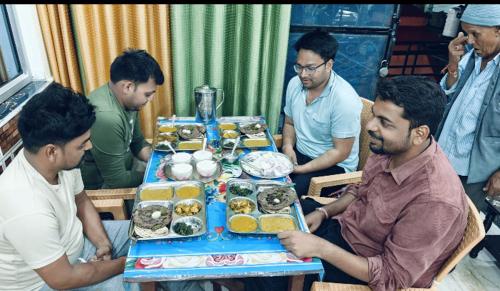 a group of men sitting around a table with food at maa kalishila home stay in Ukhimath