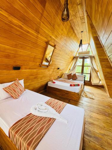 two beds in a room with wooden walls at Sigiri Tarushan Home Stay in Sigiriya
