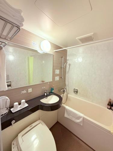 a bathroom with a toilet and a sink and a tub at Shizutetsu Hotel Prezio Shizuoka Ekinan in Shizuoka