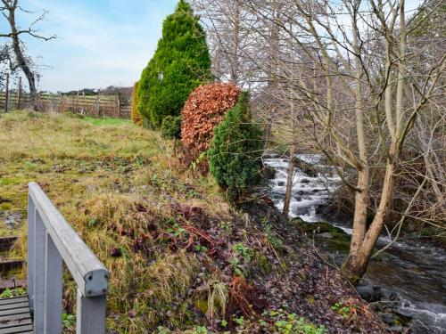 a path next to a river with a fence at The Smithy in New Galloway
