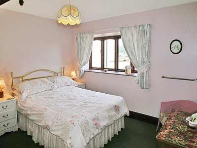 a white bedroom with a bed and a window at Dove Cottage in Minehead