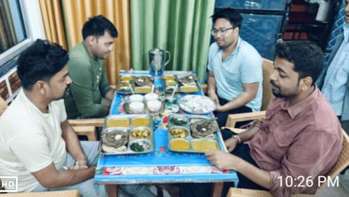 a group of men sitting around a table of food at maa kalishila home stay in Ukhimath