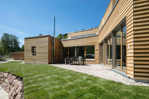 a wooden house with a patio and a lawn at Schwarzwaldstrand Ferienwohnungen in Bad Herrenalb