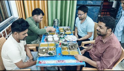 a group of men sitting around a table with food at maa kalishila home stay in Ukhimath