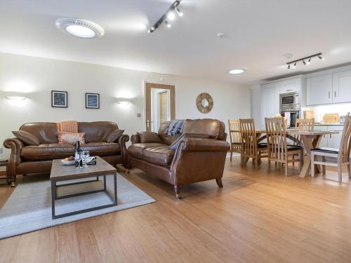 a living room with couches and a table and a kitchen at The Bunker in Sennen