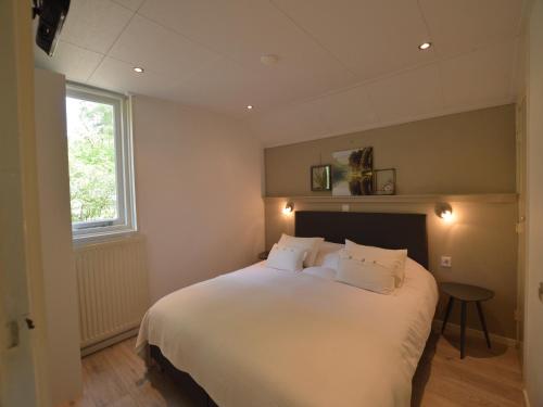 een slaapkamer met een groot wit bed met een raam bij Romantic Forest Retreat with Sauna in Stramproy