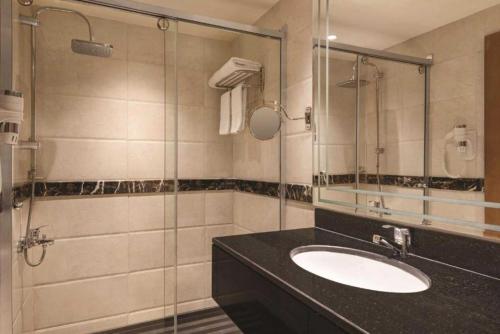 a bathroom with a sink and a glass shower at Dancenter Red Sea Fountain Alhamra Vivid Plaza Hotel in Jeddah