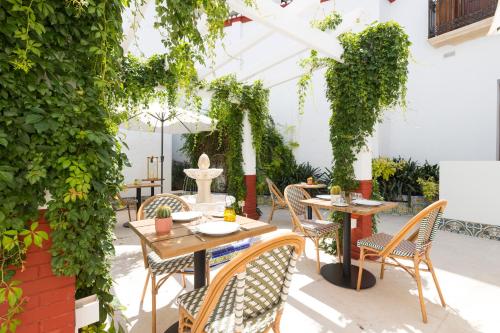 a patio with tables and chairs and ivy at Hotel La Marsellesa in Pego