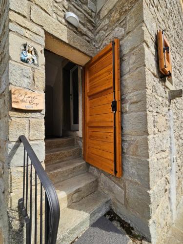 - une porte en bois dans un bâtiment en pierre avec des escaliers dans l'établissement La Coccola del Borgo, à Fanano