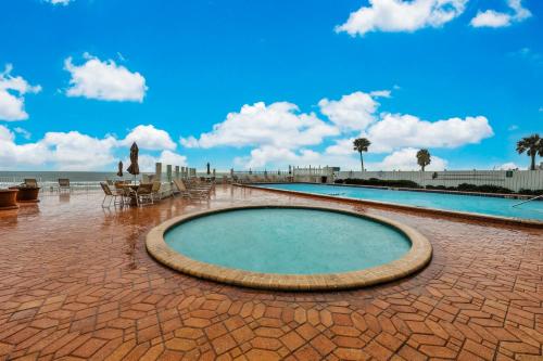 a swimming pool on a brick patio next to the ocean at Ocean Jewel Condo Unit 303 in Daytona Beach