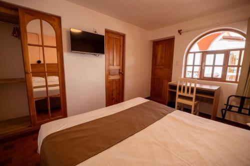 a bedroom with a bed and a desk and a window at San Sebastian Hotel Boutique in Huaraz