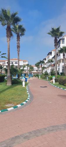 a walkway in a park with palm trees and buildings at Garden Beach 2 in Sidi Rahal