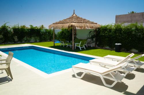 a pool with chairs and a table and a umbrella at Villa Yasmin in Temlale