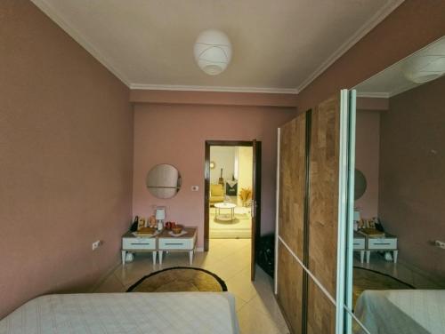 a bedroom with a bed and a table and a mirror at White House Korçë Guesthouse in Maliq