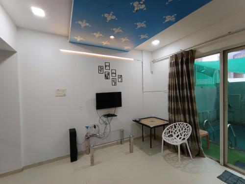 a room with a table and a tv and a chair at Sky line villa, Lonavla in Lonavala