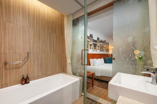 a bathroom with a tub and a sink and a bed at Hanoi Golden Holiday Hotel in Hanoi