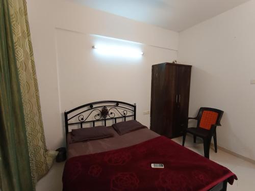 a bedroom with a red bed and a chair at Sky line villa, Lonavla in Lonavala