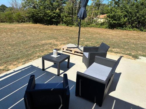 a patio with chairs and an umbrella and a table at Maison La Vigne in Marcillac-Saint-Quentin