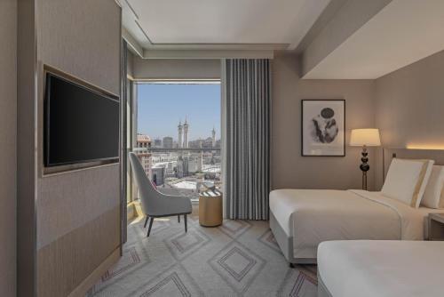 a hotel room with a bed and a flat screen tv at Jumeirah Jabal Omar Makkah in Makkah
